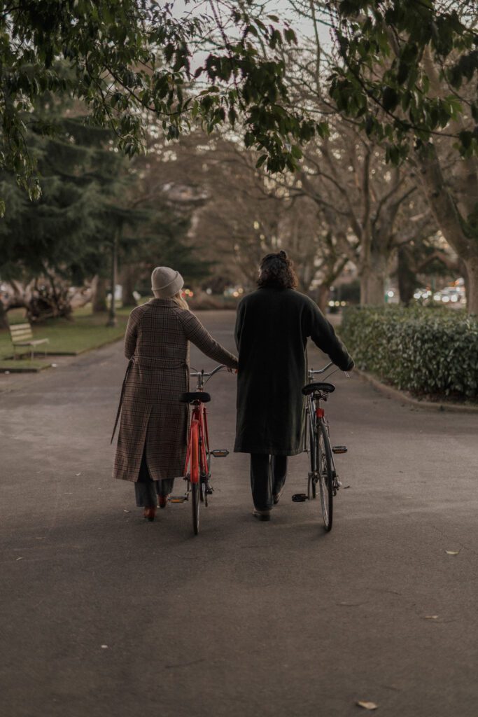 two friends walking bikes down a path